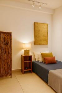 Un dormitorio con una cama y una mesa con una lámpara. en Casa Rocka Boutique Isla Mujeres, en Isla Mujeres