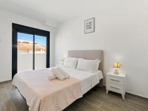 a white bedroom with a white bed and a window at Holiday Home Green Garden II-2 by Interhome in Pilar de la Horadada