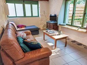 a living room with a leather couch and a table at Holiday Home La Longère by Interhome in Trémaouézan