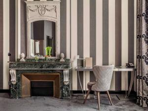 a room with a fireplace and a mirror and a chair at La Cour des Consuls Hotel & Spa Toulouse - MGallery Collection in Toulouse +188 photos