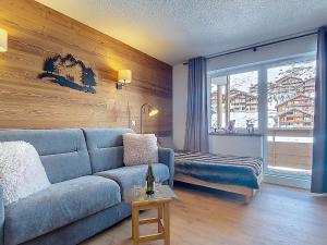 a living room with a blue couch and a window at Studio Les Olympiades-16 by Interhome in Val Thorens +17 photos