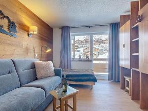 a living room with a blue couch and a window at Studio Les Olympiades-16 by Interhome in Val Thorens