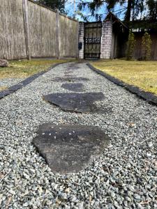 Eine Kiesauffahrt mit zwei Schlaglöchern vor einem Zaun in der Unterkunft Peace, Pines & Pure Air in Vangaži