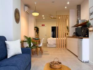 a living room with a blue couch and a kitchen at Ruzafa & Oceanografic Suites by Illetes Flats in Valencia