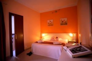 ein Schlafzimmer mit einem Bett und einer orangefarbenen Wand in der Unterkunft Hotel Etrusco in Rio Marina