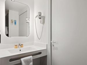 a white bathroom with a sink and a mirror at ibis Styles Paris Charles de Gaulle Airport in Roissy-en-France +161 photos