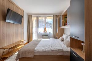une chambre avec un lit blanc et une télévision dans l'établissement Pirin Sense Apartment Complex, à Bansko