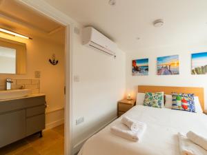 a bedroom with a white bed and a sink at Holiday Home Shanty Cottage by Interhome in Mevagissey