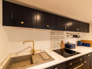a kitchen with black cabinets and a sink at Holiday Home Shanty Cottage by Interhome in Mevagissey