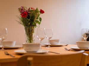 a table with a vase of flowers and wine glasses at Holiday Home Shanty Cottage by Interhome in Mevagissey +44 photos
