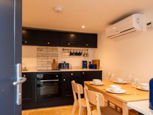 a kitchen with a wooden table with chairs and a kitchen with black cabinets at Holiday Home Shanty Cottage by Interhome in Mevagissey