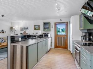 a kitchen with white walls and a wooden floor at Holiday Home Naema - 500m from the sea by Interhome in Østerby Havn