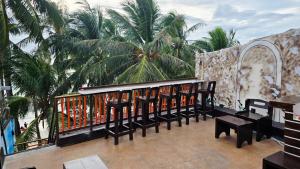 un balcón con mesas, bancos y palmeras en Aurora Hostel Inn, en Boracay