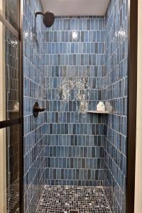 a blue tiled shower with a glass door at Modern Studio for 4 Near Killington with Fireplace, Summer Pool & EV Charger in The Woods