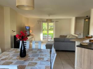 eine Küche und ein Wohnzimmer mit einer Vase aus Blumen auf dem Tisch in der Unterkunft Maison tout confort avec piscine chauffée au bord des rives de la Dordogne in Argentat