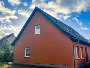 a red house with two windows and a blue roof at Kröslin Apartments in Kröslin +39 photos