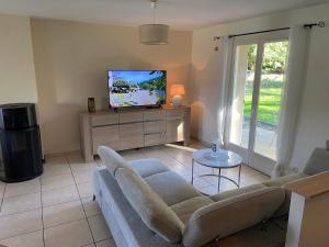 ein Wohnzimmer mit Sofa und Fernseher in der Unterkunft Maison tout confort avec piscine chauffée au bord des rives de la Dordogne in Argentat