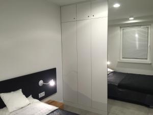 a bedroom with a bed and a large white cabinet at MOHO apartament in Dziwnówek