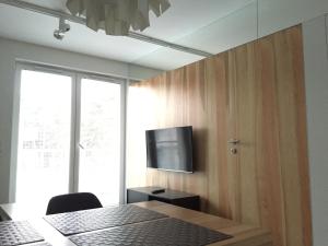 een kamer met een televisie aan een muur met een tafel bij MOHO apartament in Dziwnówek