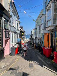 a woman walking down a street next to buildings at The Locker, 2 bed apartment in Falmouth in Falmouth