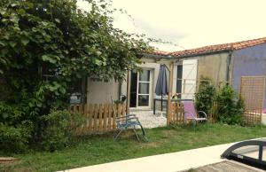 a house with two chairs and an umbrella in the yard at Au Bal des Oiseaux in Chavagnes-en-Paillers