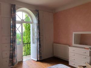 a room with a window and a dresser with a television at Villa Mon But - Maison de maître du 19ème siècle in Hagetmau +2 photos