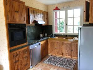 a kitchen with wooden cabinets and a sink and a refrigerator at Villa Mon But - Maison de maître du 19ème siècle in Hagetmau