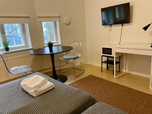 a living room with a table and a tv at Kotimaailma Villa Hortus - Cosy Studio for 2 in Turku