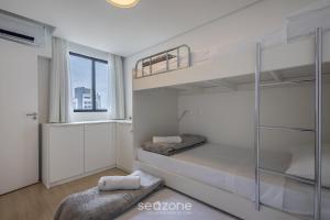 a bedroom with two bunk beds and a window at Estadia completa com piscina e academia a 400m da Praia da Armação - SKL in Penha +219 photos