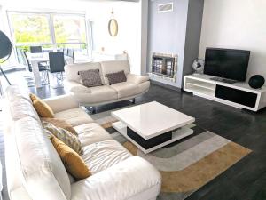 a living room with white couches and a tv at L'écrin champêtre, séjour chic et cosy in Waldolwisheim