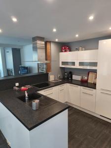 eine Küche mit weißen Schränken und einer schwarzen Arbeitsplatte in der Unterkunft L'écrin champêtre, séjour chic et cosy in Waldolwisheim