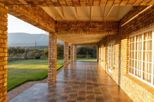 un porche de ladrillo con vistas a un campo en Geluk Farmhouse, en Somerset East