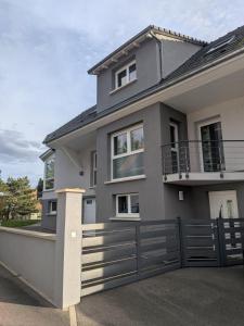 ein graues Haus mit einem Zaun davor in der Unterkunft L'écrin champêtre, séjour chic et cosy in Waldolwisheim