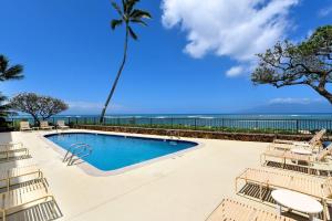 a swimming pool with chairs and a view of the ocean at Kahana Reef 111 · KR 111 Renovated OceanFront Condo Romantic Get in Kahana