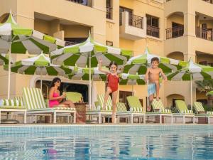 Un grupo de niños de pie sobre sillas junto a una piscina en Pullman Resort Al Marjan Island, en Ras al Khaimah
