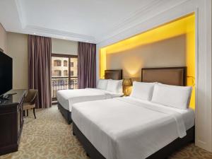 um quarto de hotel com duas camas e uma televisão em Pullman Resort Al Marjan Island em Ras al-Khaimah