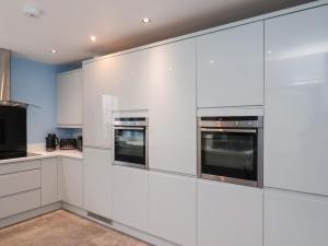 Kingfisher House في ستيثيس: مطبخ مع دواليب بيضاء واجهزة ستانلس ستيل