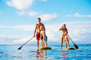a man and a woman and a child on paddle boards in the water at Maui Sands Seaside 713 · MSS 713 Charming 1BD Near Beach in Kahana