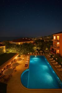 Una piscina de noche con sillas y sombrillas. en Treekos Boutique Hotel Istanbul Airport, en Karaburun