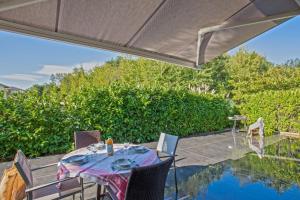 eine Terrasse mit Tisch und Stühlen und einem Pool in der Unterkunft Villa Jardins de la Mer in Poggio-Mezzana