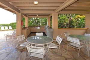 a patio with two tables and chairs and a kitchen at Paki Maui 424 · PM424 BeachFront 2BD w Ocean View in Kahana