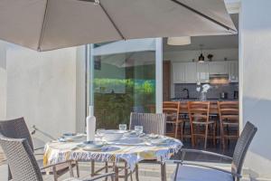 ein Esszimmer mit einem Tisch und Stühlen mit einem Sonnenschirm in der Unterkunft Villa Jardins de la Mer in Poggio-Mezzana + 26 Fotos
