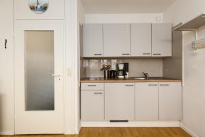 a white kitchen with white cabinets and a sink at Marina Wendtorf Hafenblick in Wendtorf