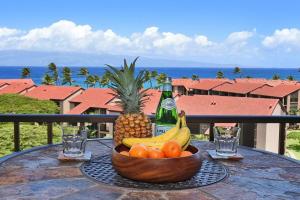 a bowl of fruit on a table with a bottle of champagne at Kaanapali Shores 836 · KS 836 Spacious Studio Kaanapali Oceanfro in Kahana