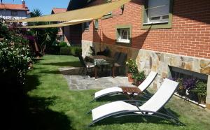 a backyard with lawn chairs and a table and a building at Villa La Perla De Sonabia in Oriñón