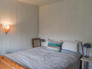 een slaapkamer met een bed met een blauw dekbed en twee lampen bij Rowan Cottage in Rosedale Abbey