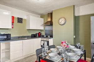 a kitchen with a table and a clock on the wall at Large House with Parking and Garden - Sleeps 7 in Maidstone