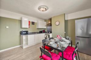 a kitchen and dining room with a table and red chairs at Large House with Parking and Garden - Sleeps 7 in Maidstone