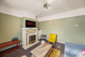 a living room with a fireplace and a yellow chair at Large House with Parking and Garden - Sleeps 7 in Maidstone +7 photos