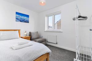 a bedroom with a bed and a chair and a window at Finest Retreats - Ffordd Y Meillion in Llanelli